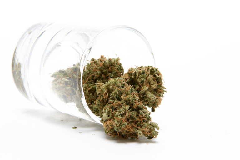 Click to see a larger version of the image Cannabis nugs in clear glass jar on white background.