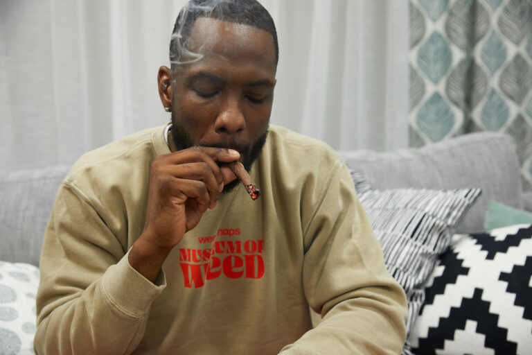 Click to see a larger version of the image Man smoking blunt on couch.