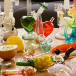 Table full of glass bongs, pipes, and other glass smoking accessories.