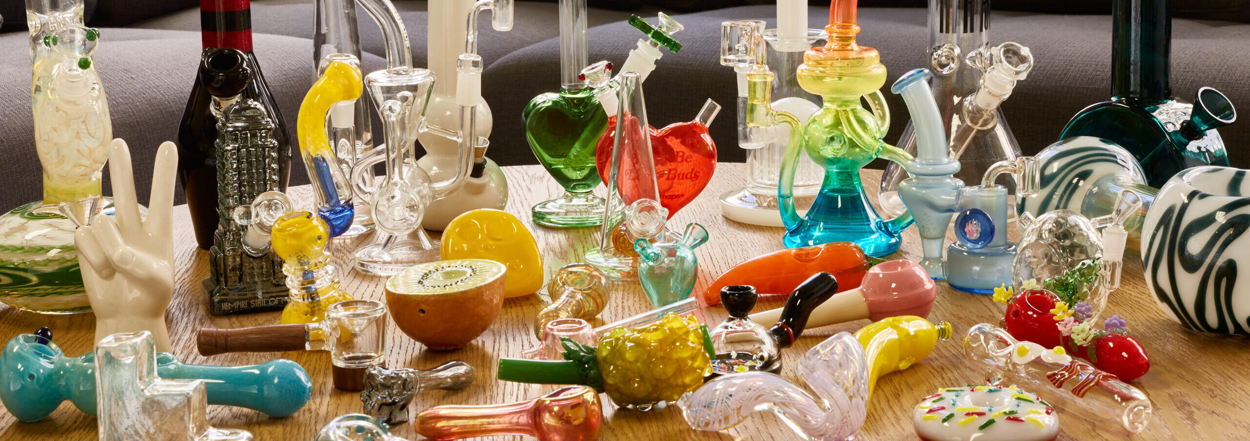 Table full of glass bongs, pipes, and other glass smoking accessories.