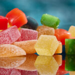 Pile of different gummy edibles on teal background