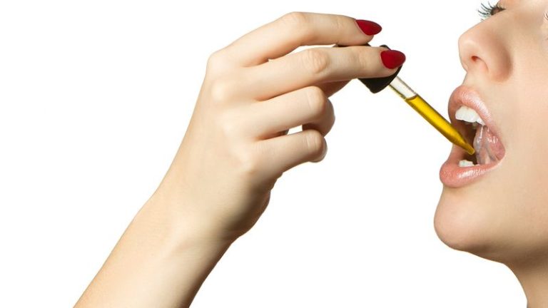 woman placing cbd oil under tongue
