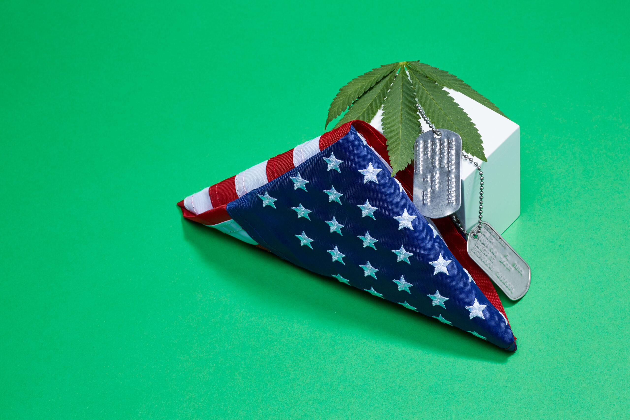 A folded American flag with dog tags and a weed leaf