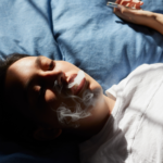 woman vaping on bed